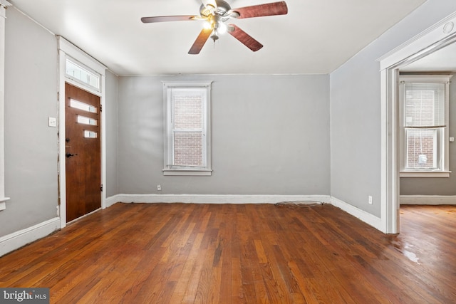 foyer entrance with dark wood-style floors, ceiling fan, and baseboards