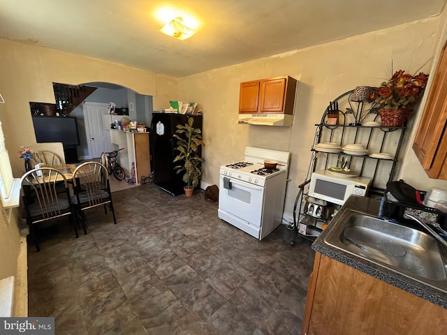 kitchen with black refrigerator, white gas stove, and sink