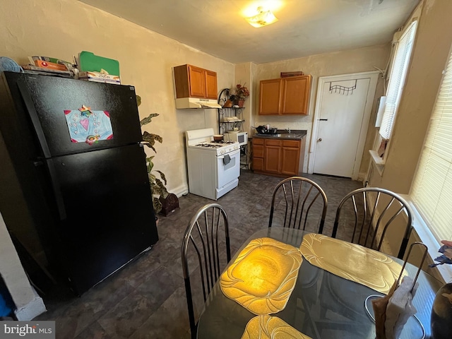 kitchen with black fridge, white gas range, and sink