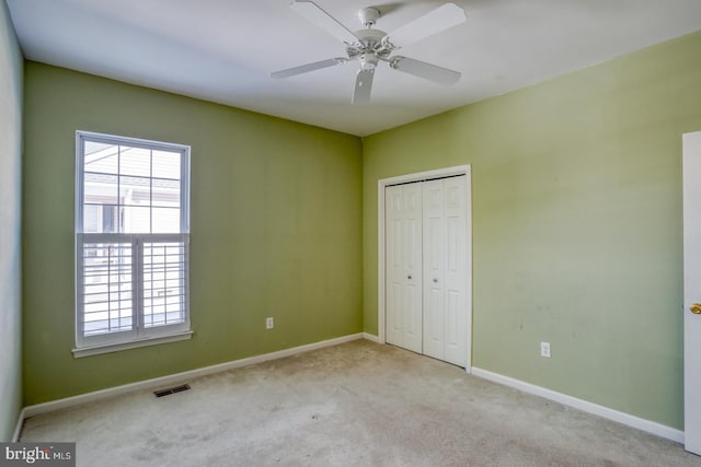 unfurnished bedroom featuring ceiling fan, a closet, and light carpet