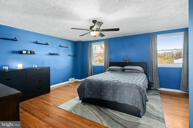 bedroom with multiple windows, ceiling fan, and hardwood / wood-style floors