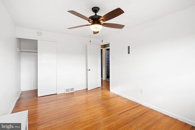 unfurnished bedroom featuring hardwood / wood-style floors, a closet, and ceiling fan