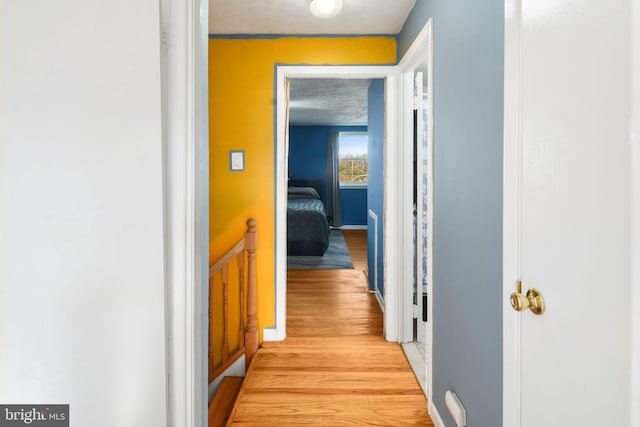 hall with a textured ceiling and light wood-type flooring