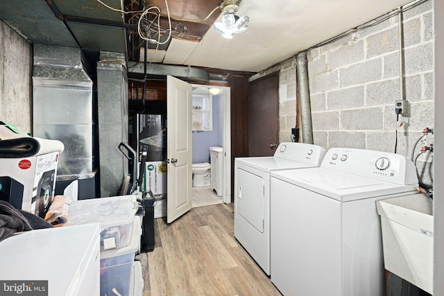 laundry room with sink, light hardwood / wood-style flooring, and washing machine and clothes dryer