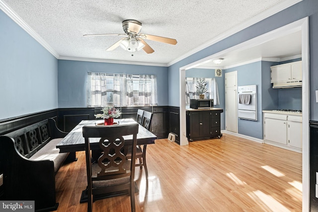 dining space featuring a textured ceiling, ceiling fan, crown molding, and light hardwood / wood-style flooring