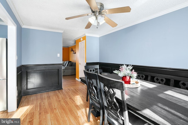 dining room featuring a textured ceiling, light hardwood / wood-style floors, ceiling fan, and ornamental molding