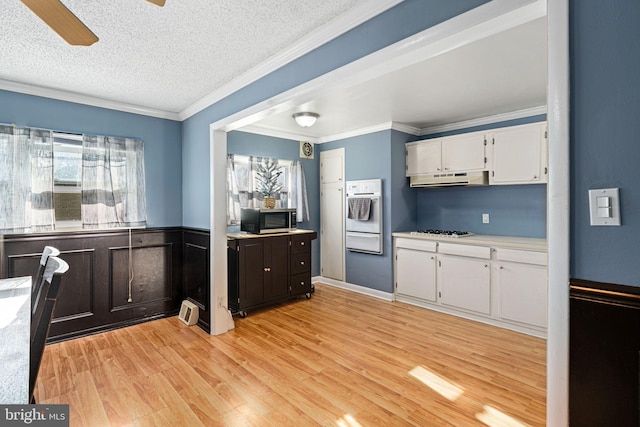 kitchen featuring white cabinetry, light hardwood / wood-style flooring, crown molding, a textured ceiling, and white appliances