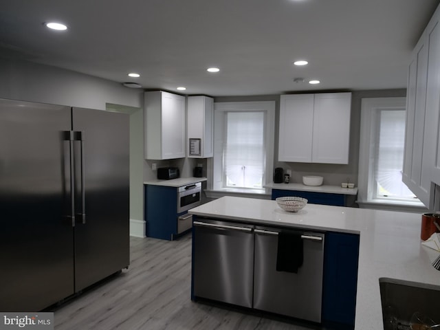 kitchen featuring white cabinets, appliances with stainless steel finishes, light wood-type flooring, and blue cabinetry