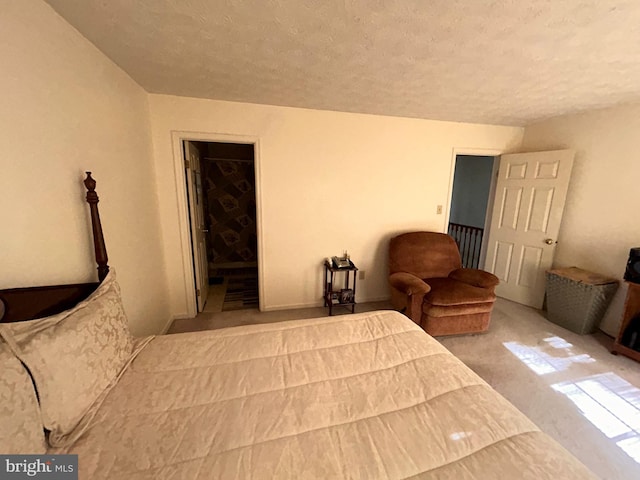 carpeted bedroom with a spacious closet, a textured ceiling, and a closet