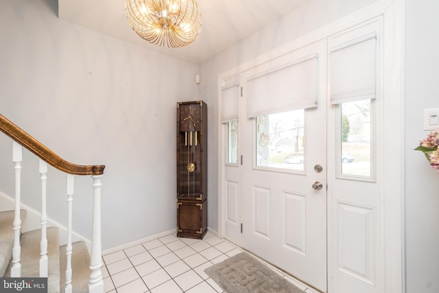 entrance foyer featuring an inviting chandelier, baseboards, light tile patterned floors, and stairway