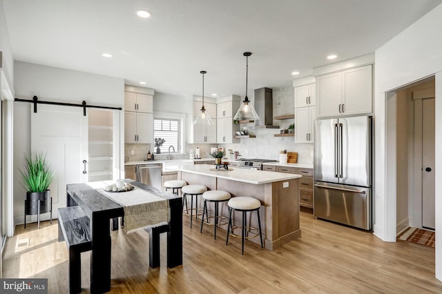 kitchen with high end appliances, white cabinetry, a barn door, and a kitchen island