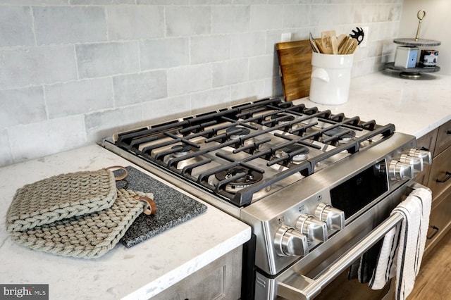 room details featuring decorative backsplash and stainless steel gas range