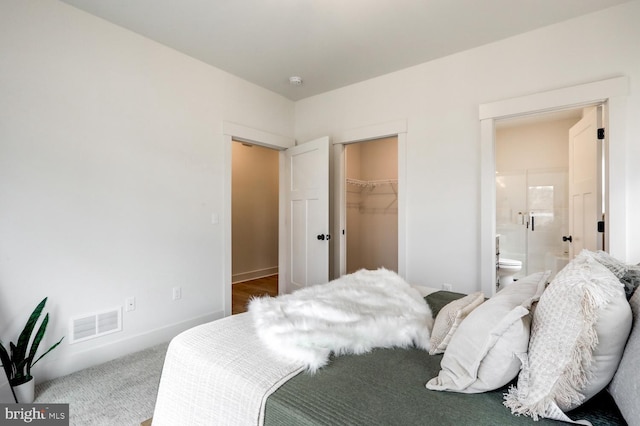 bedroom featuring carpet flooring, ensuite bathroom, a spacious closet, and a closet