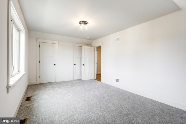 unfurnished bedroom with two closets and carpet