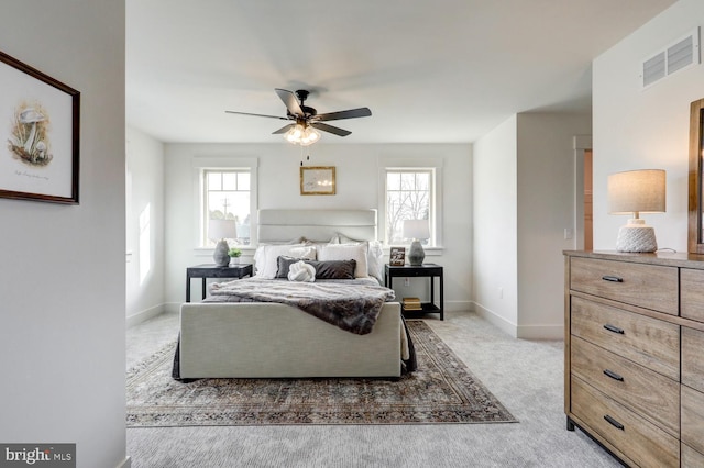 carpeted bedroom featuring multiple windows and ceiling fan