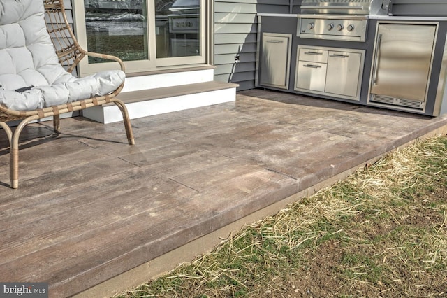 wooden deck featuring an outdoor kitchen, a grill, and a patio area