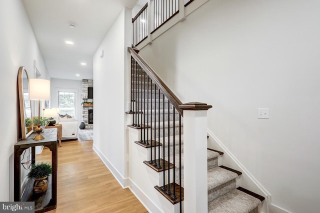 stairway with wood-type flooring and a fireplace