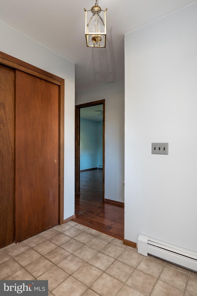 interior space with baseboard heating, a closet, and a notable chandelier