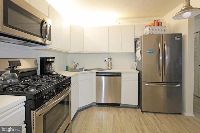 kitchen featuring white cabinets, appliances with stainless steel finishes, light wood-type flooring, and sink