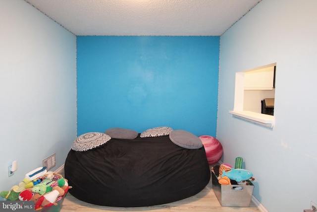 bedroom featuring light hardwood / wood-style flooring and a textured ceiling