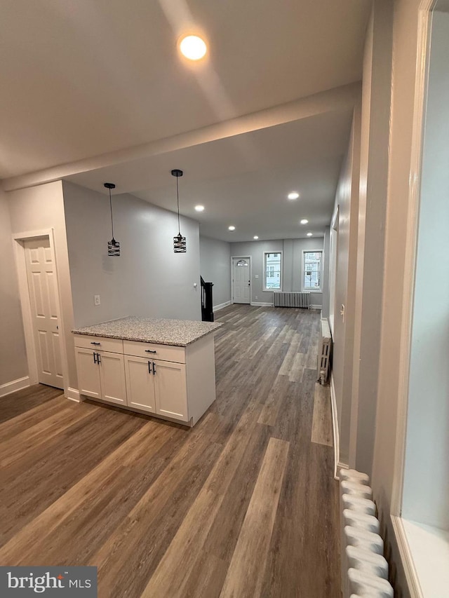 interior space featuring light stone countertops, dark hardwood / wood-style flooring, radiator heating unit, white cabinetry, and hanging light fixtures