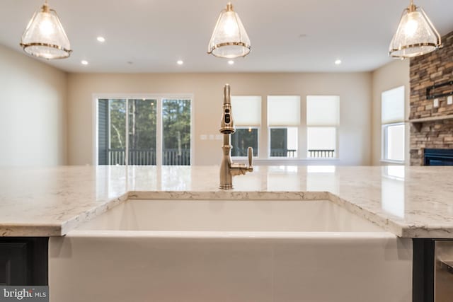 kitchen with a stone fireplace, sink, and hanging light fixtures