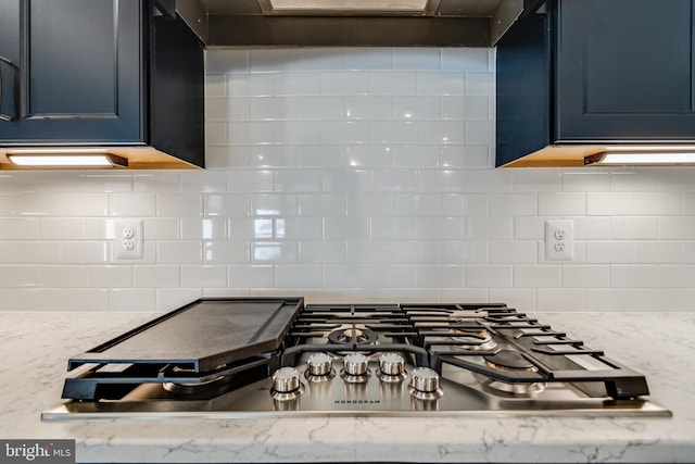 kitchen featuring backsplash, light stone counters, and stainless steel gas cooktop