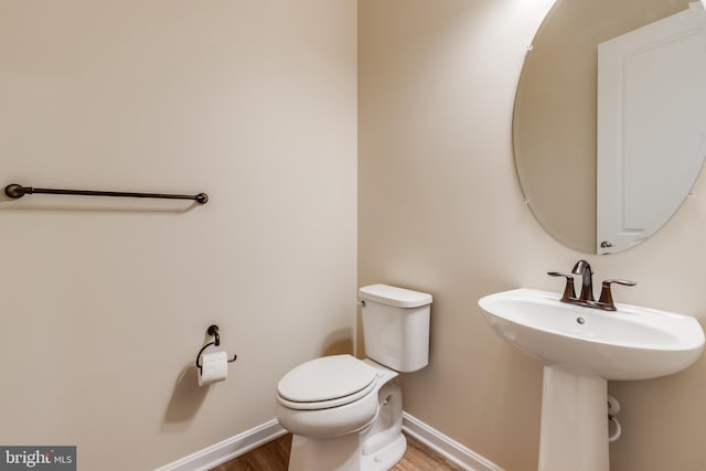 bathroom with wood-type flooring, toilet, and sink