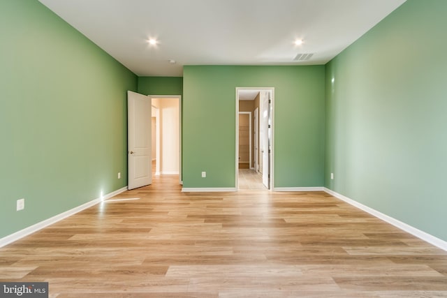 unfurnished bedroom with ensuite bathroom and light hardwood / wood-style flooring