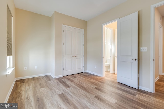 unfurnished bedroom featuring ensuite bathroom, light hardwood / wood-style floors, and a closet