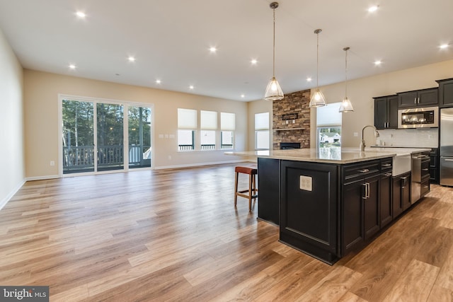 kitchen featuring a large island, stainless steel appliances, hanging light fixtures, and light hardwood / wood-style flooring