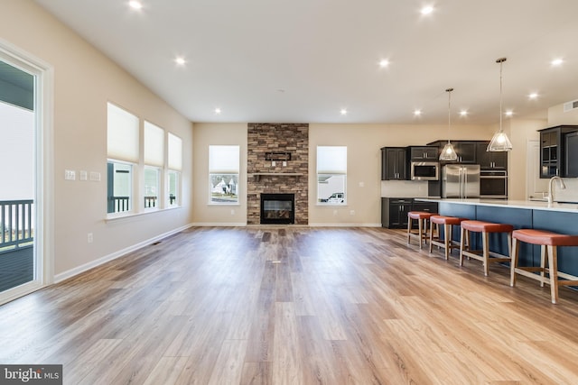 living room featuring light hardwood / wood-style floors, a stone fireplace, and sink