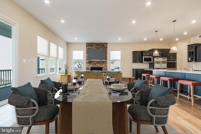 interior space featuring pendant lighting, a breakfast bar, sink, appliances with stainless steel finishes, and light hardwood / wood-style floors