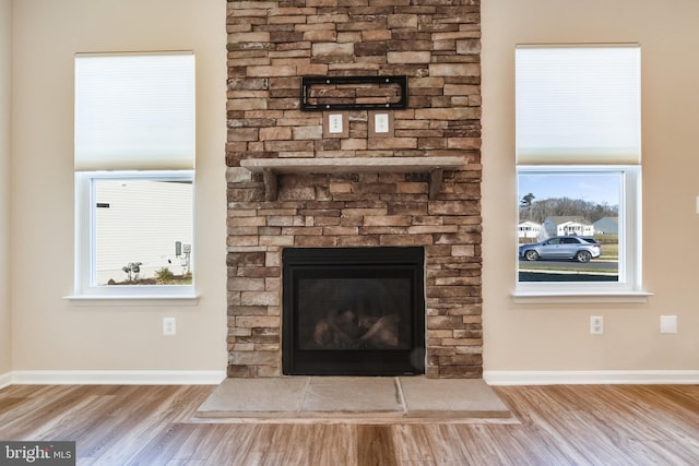 interior details featuring a stone fireplace and wood-type flooring