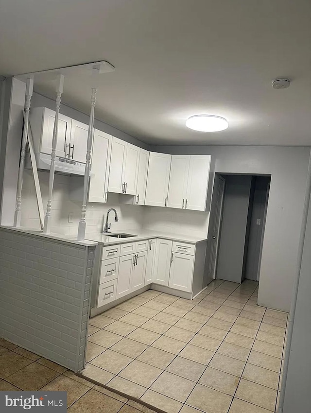 kitchen with light tile patterned floors, white cabinetry, and sink