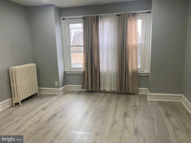 spare room featuring radiator heating unit and hardwood / wood-style flooring