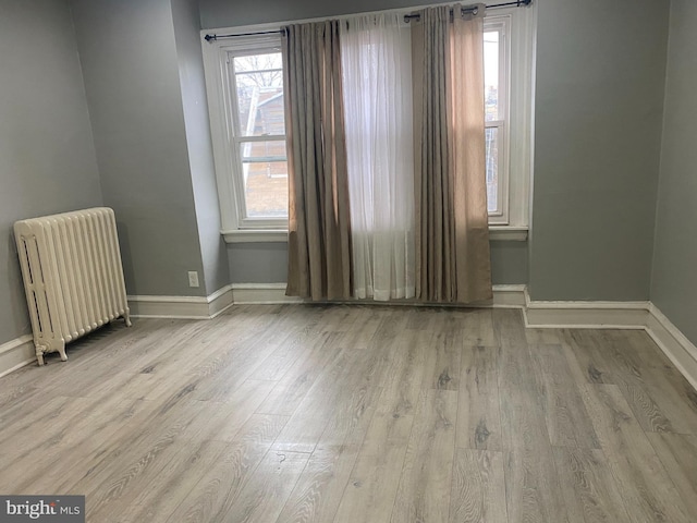 unfurnished room with radiator heating unit and light hardwood / wood-style floors