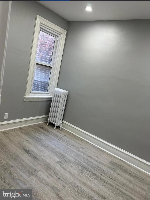 unfurnished room featuring radiator heating unit and light wood-type flooring