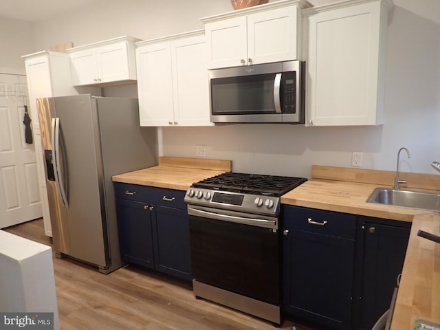 kitchen featuring appliances with stainless steel finishes, white cabinets, sink, and butcher block counters