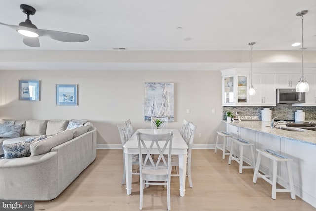 dining room with light hardwood / wood-style flooring, ceiling fan, and sink