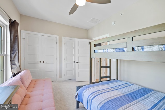 carpeted bedroom with ceiling fan and two closets