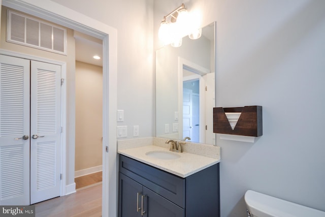 bathroom with vanity, toilet, and wood-type flooring