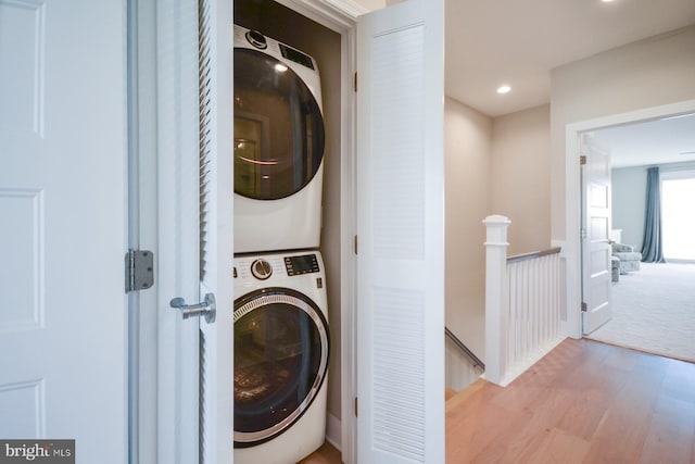 laundry area featuring stacked washer and dryer and light hardwood / wood-style flooring