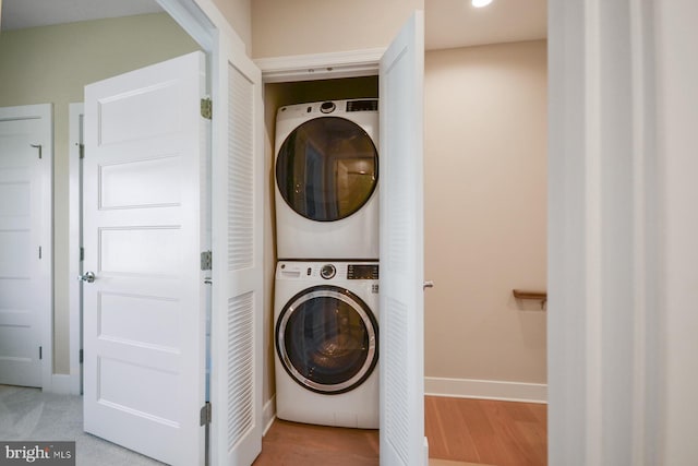 washroom with stacked washer / drying machine and hardwood / wood-style flooring