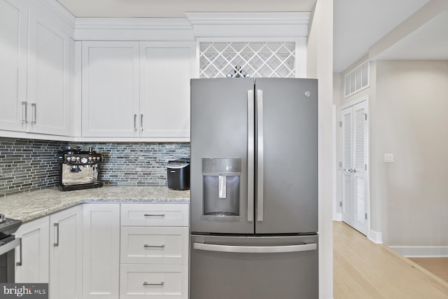 kitchen with backsplash, light stone counters, white cabinetry, and stainless steel refrigerator with ice dispenser