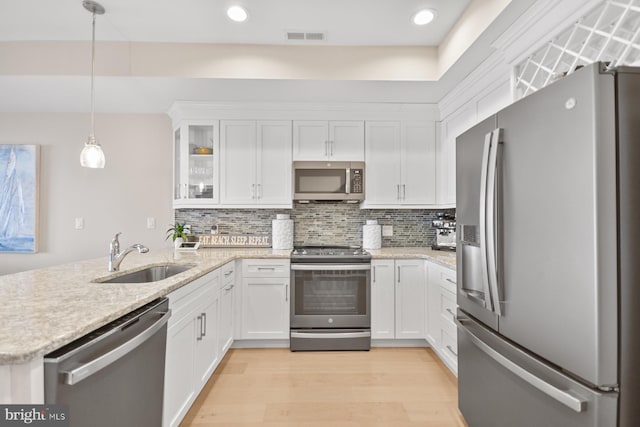 kitchen with stainless steel appliances, sink, pendant lighting, light hardwood / wood-style flooring, and white cabinets