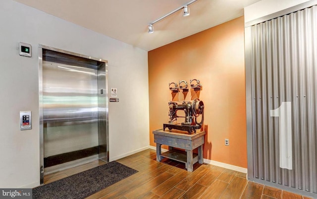 entrance foyer with hardwood / wood-style flooring, elevator, and track lighting