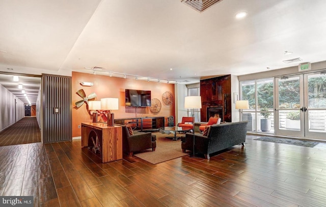 living room with dark hardwood / wood-style flooring, rail lighting, and french doors