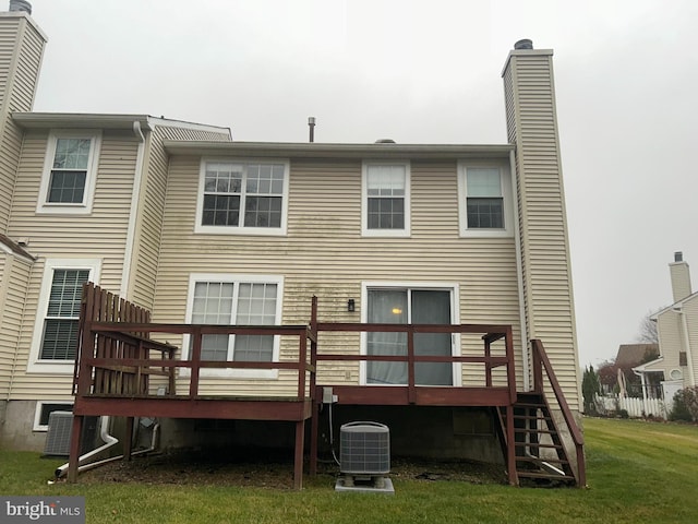 rear view of property with central AC unit, a wooden deck, and a yard