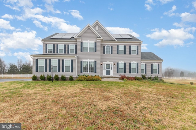 view of front of house featuring solar panels and a front lawn